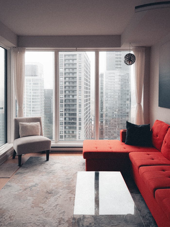 Stylish living room featuring a red couch and city skyscraper view.